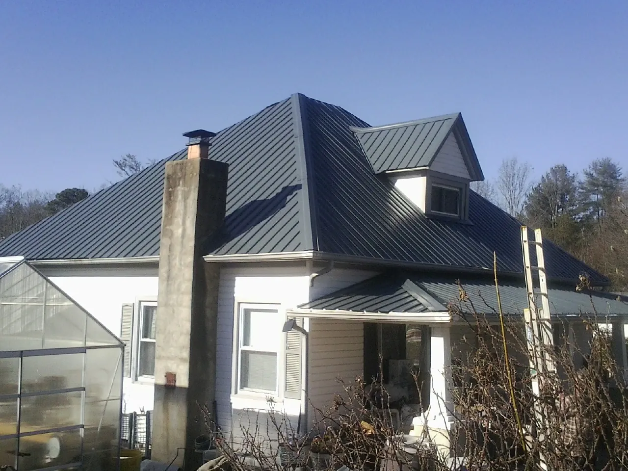 Dark blue standing seam metal roof on a white farmhouse with dormer — Slate & Tile Roof Repair by Roofing Brothers in Blounts Creek