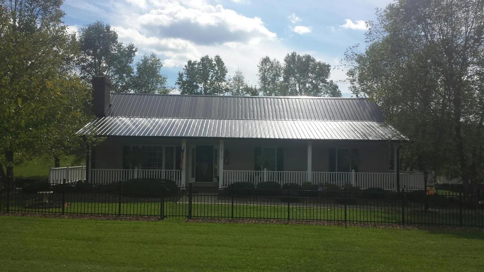 Gray metal roof on a brick ranch with a full width front porch — Gutter Guard Installation work by our crew in Blounts Creek