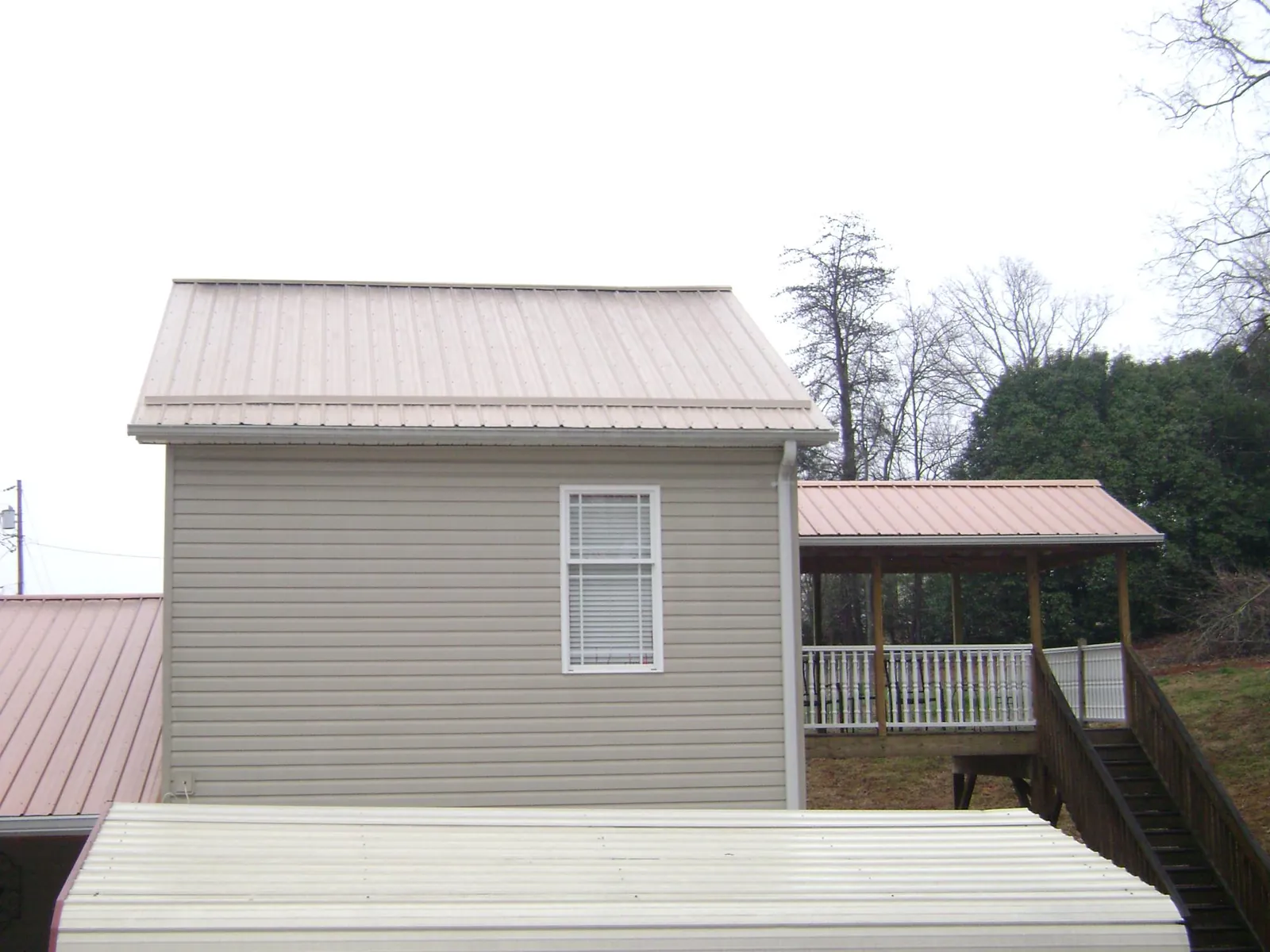 Tan metal roofs on a two story addition and attached porch, from a Roof Replacement job in Blounts Creek