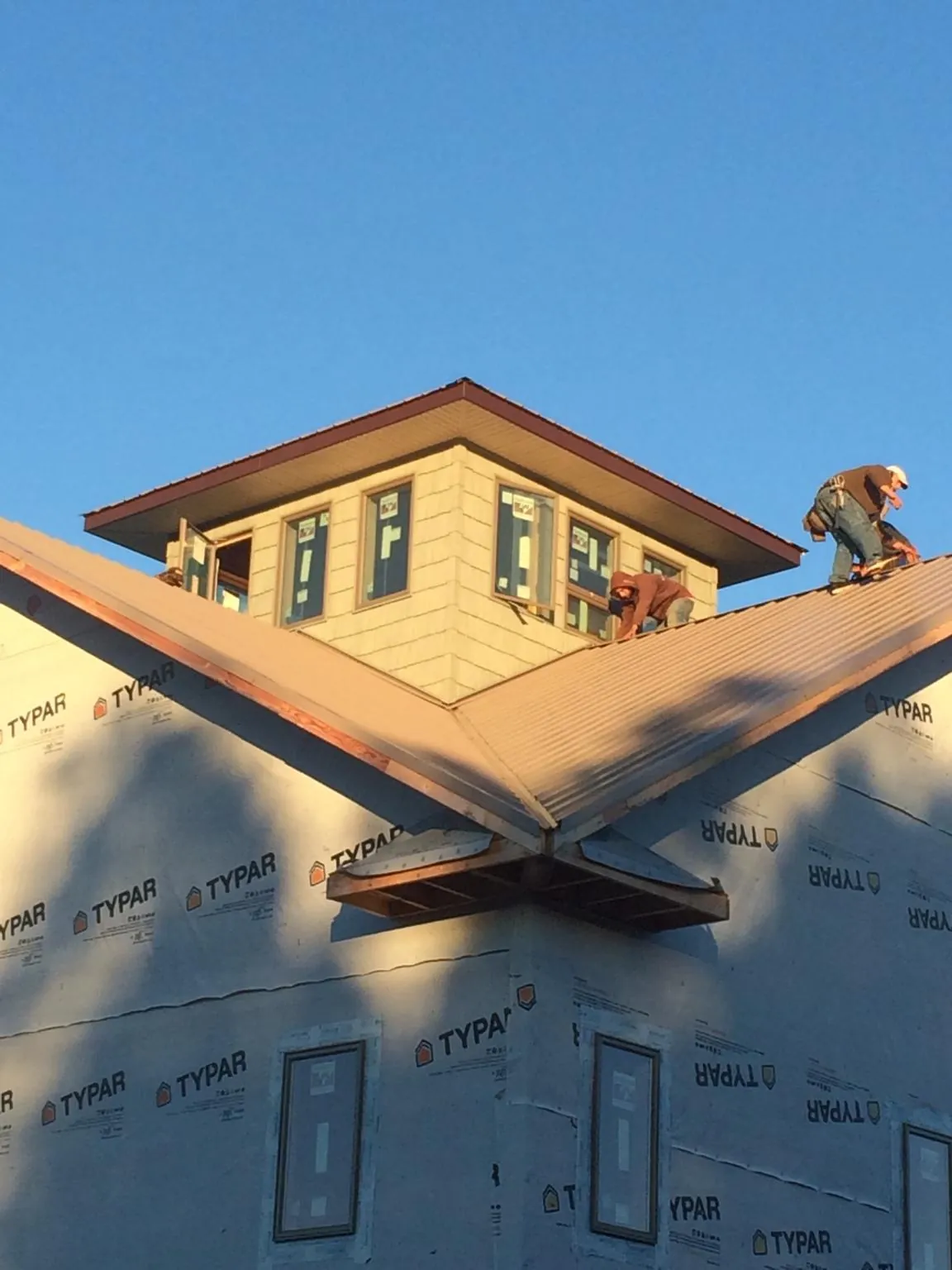 Roofers working around a rooftop cupola on a new metal roof at sunset — Roof Waterproofing in Blounts Creek by Roofing Brothers